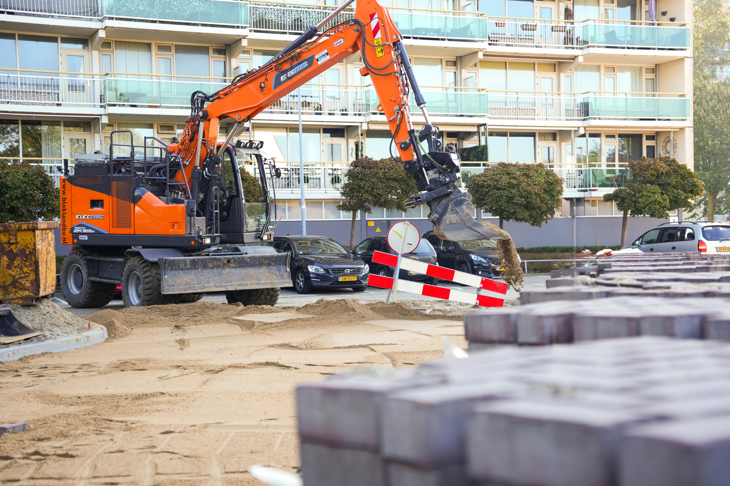 Graafmachine van Hoogendijk Bestratingen met stapels stenen bij bestratingsproject