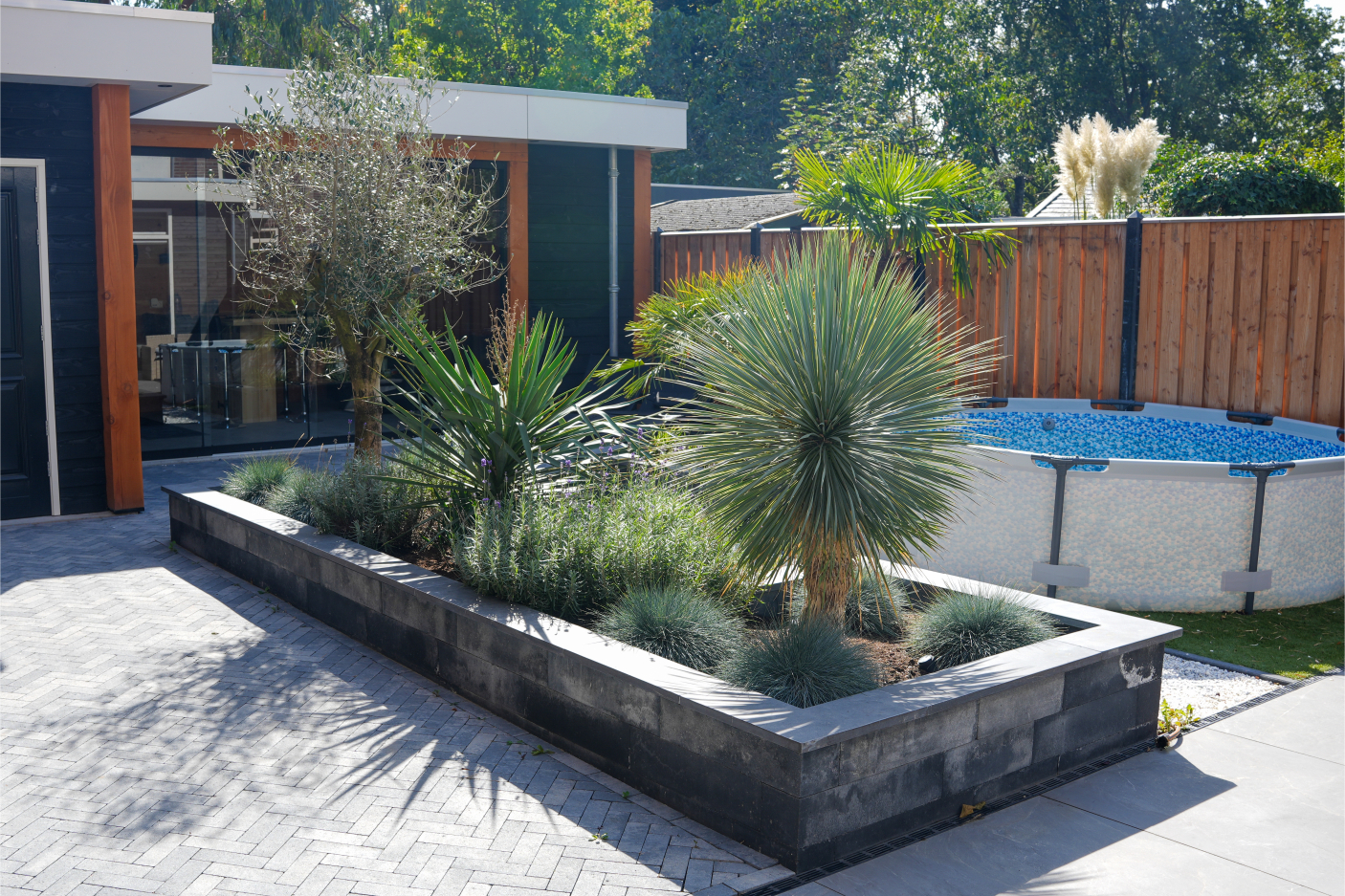 Grote stenen plantenbak naast strak aangelegd straatwerk